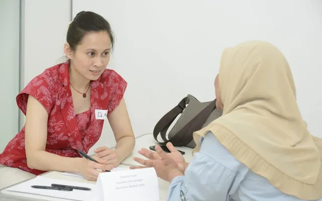 Dr Kartini Farah Rahim talking with a patient during a dermatology consultation