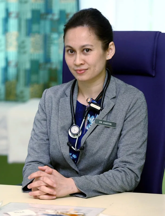 Dr Kartini Farah Rahim seated at her desk with a stethoscope