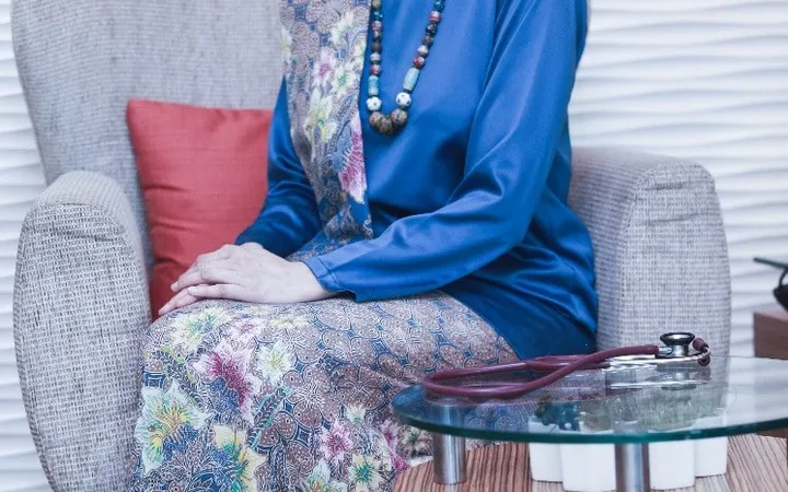 Dr Kartini seated in a blue baju kurung